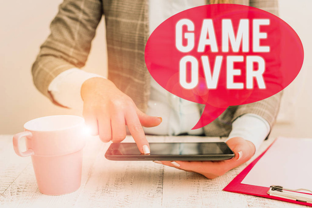 Text sign showing Game Over. Conceptual photo A situation in a particular sport that reach his finals or ending Business woman sitting with mobile phone and cup of coffee on the table. - Фото, зображення
