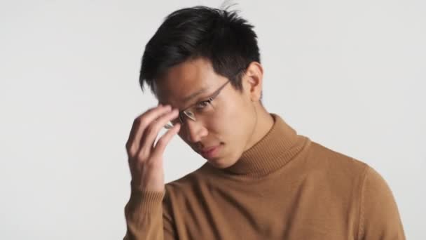 młody atrakcyjny stylowy Azji człowiek w okulary prostuje włosy pewnie patrząc w aparat  - Materiał filmowy, wideo