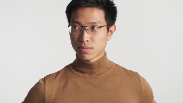 Молодой красивый стильный азиатский мужчина в очках уверенно флиртует перед камерой. Зрительный контакт
 - Кадры, видео