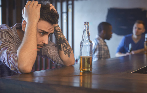 Troubled young man sitting alone at bar - Foto, imagen