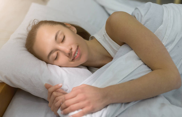 Piękna młoda kobieta śpi w łóżku wygodnie - Zdjęcie, obraz