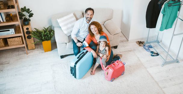Happy family going on vacation, sitting on couch with suitcases. - Foto, imagen