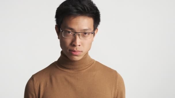 Young serious asian man in eyeglasses aggressively showing index finger and  threatening on camera isolated. You in deep trouble expression - Footage, Video