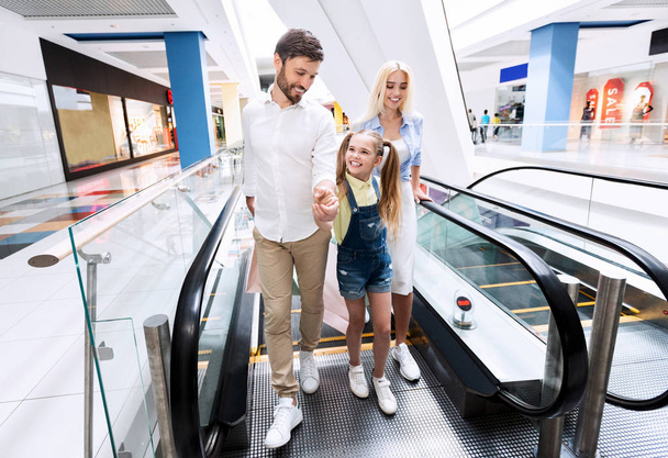 Семья делает покупки выходя из эскалатора холдинг сумки в гипермаркете
 - Фото, изображение