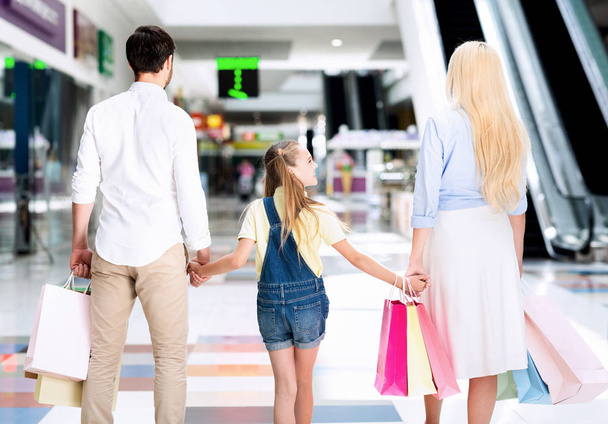 Famiglia irriconoscibile che cammina mani in mano nel centro commerciale, vista posteriore
 - Foto, immagini