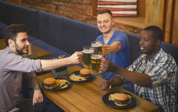 Верхний вид товарищей звенящие кружки с пивом в пабе
 - Фото, изображение
