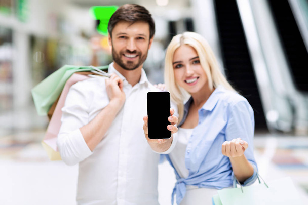 Пара, що показує екран мобільного телефону, що стоїть у торговому центрі, макет
 - Фото, зображення