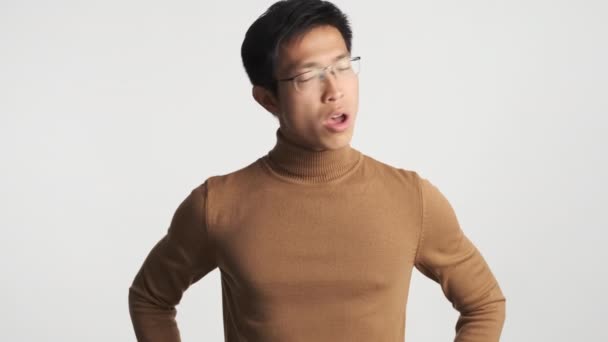 Fiatal, komoly ázsiai fickó szemüvegben, magabiztosan lóbálja a fejét. Persze semmi gesztus fehér háttér felett - Felvétel, videó