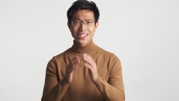 Mladý ustaraný Asiat v brýlích ukazuje izolované gesto. Prosím výraz - Záběry, video