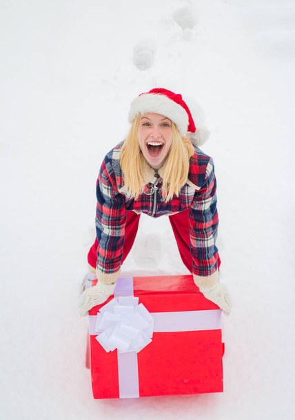 Christmas Woman holding a huge gift box. Woman present red gift box with ribbon bow isolated over white background. Big gift box. Hipster Girl with Christmas gift on snow Winter landscape. - Fotó, kép