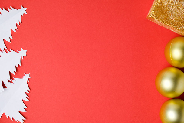 Різдвяні ялинки ручної роботи з зірками, вирізаними з білого паперу із золотим подарунком та кульками на червоному тлі з місцем для тексту
. - Фото, зображення