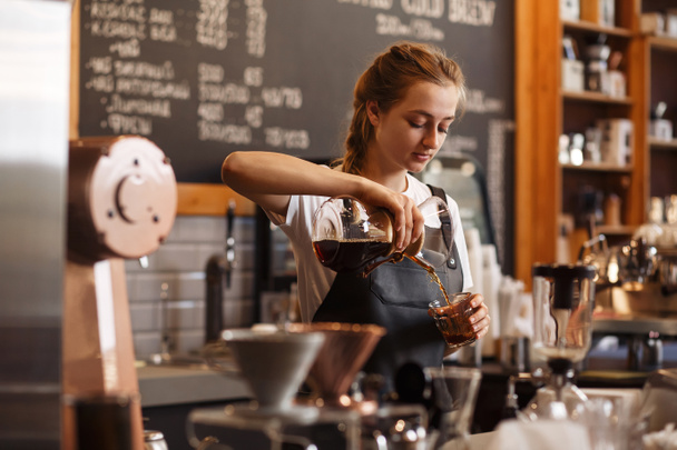 Professional barista preparing coffee using chemex pour over coffee maker and drip kettle. Young woman making coffee. Alternative ways of brewing coffee. Coffee shop concept. - Photo, Image
