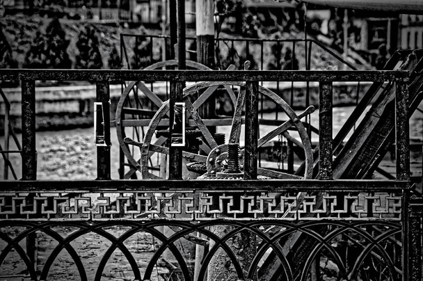Чорно-біла темна картина металевих конструкцій - мостові балончики та шлюзові ручні колеса
 - Фото, зображення