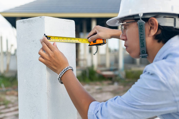 Arquiteto masculino medindo poste de parede da casa
 - Foto, Imagem