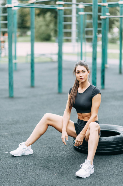 Training and posing with a tire. Beautiful athletic girl on the Playground.  - Fotografie, Obrázek