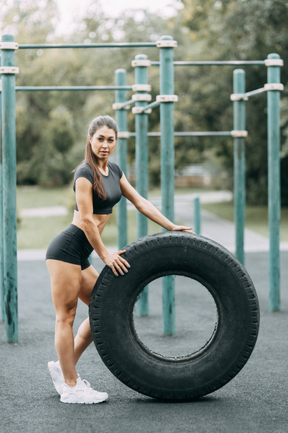 Training and posing with a tire. Beautiful athletic girl on the Playground.  - Zdjęcie, obraz