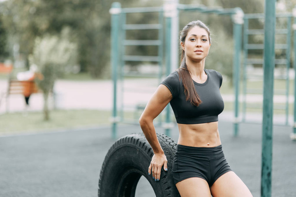 Training and posing with a tire. Beautiful athletic girl on the Playground.  - Foto, Imagen