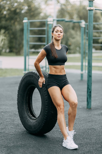 Training and posing with a tire. Beautiful athletic girl on the Playground.  - Fotoğraf, Görsel
