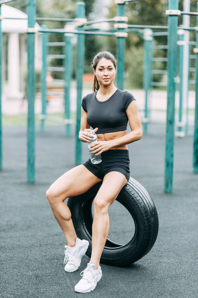 Training and posing with a tire. Beautiful athletic girl on the Playground.  - Foto, immagini
