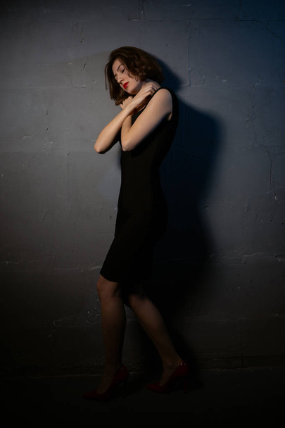 a sad woman against a dark wall - Fotografie, Obrázek