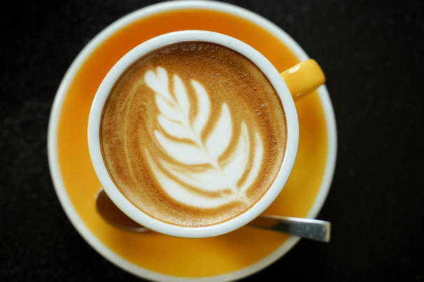 Coffee Latte leaf pattern face on black table - Foto, Bild