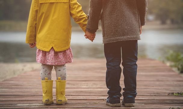 Couple girl and boy in autumn nature. Girl in yellow raincoat and boots - Photo, Image