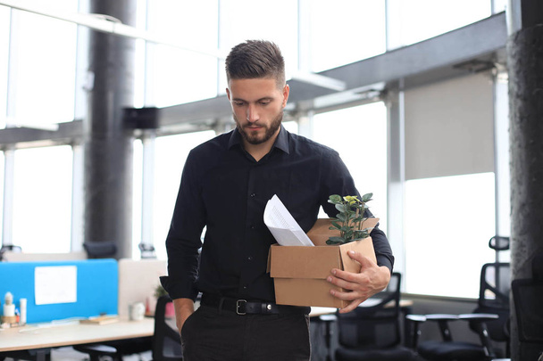 Sad dismissed worker is taking his office supplies with him from office - Photo, Image