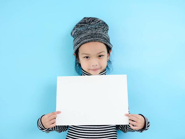 Asian girl in winter costume holding white blank paper on blue b - Foto, immagini