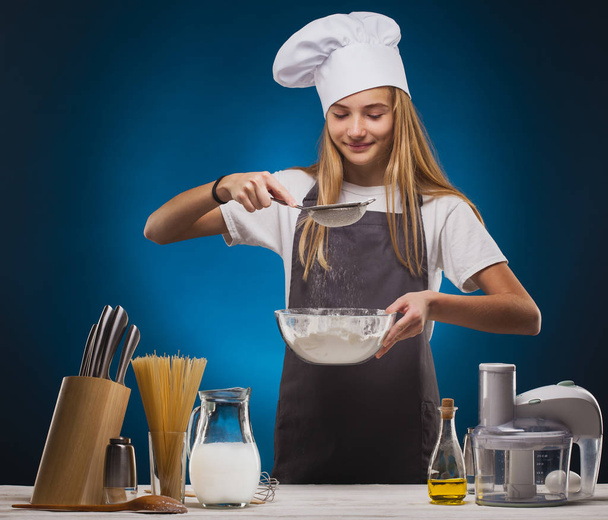 Woman Chef prepares a delicious dish on a blue background. - Zdjęcie, obraz
