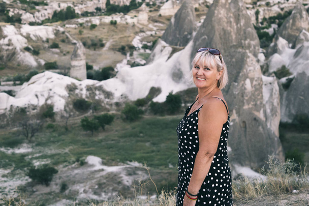 女性はトルコのカッパドキアの山の頂上に立っています。有名な石の頂上の航空写真。旅と冒険の概念. - 写真・画像