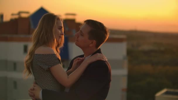 Mężczyzna i kobieta uścisk na dachu o zachodzie słońca - Materiał filmowy, wideo