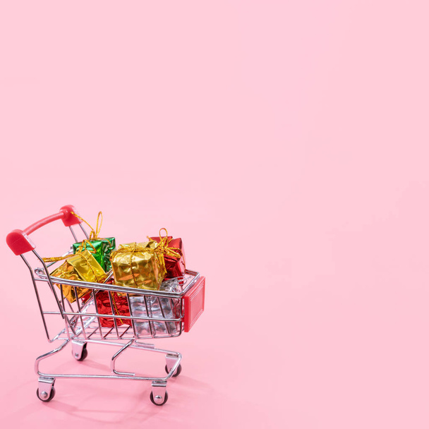 Annual sale, Christmas shopping season concept - mini red shop cart trolley full of gift box isolated on pale pink background, copy space, close up - Foto, immagini