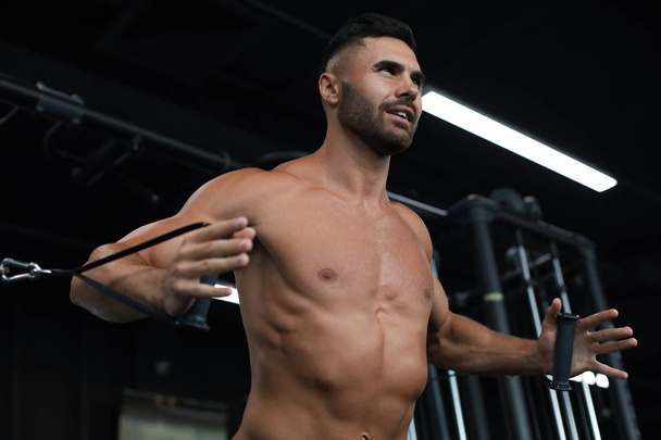 Fit i muskularny Człowiek trenuje mięśnie piersiowe na symulatorze bloku w siłowni. - Zdjęcie, obraz