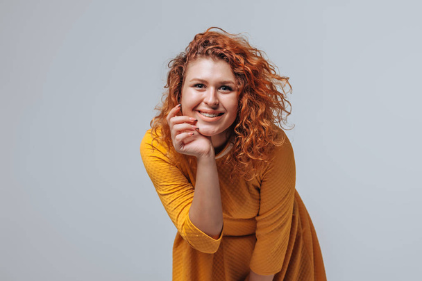 A red haired girl in a yellow dress on a light gray background s - Foto, Imagem