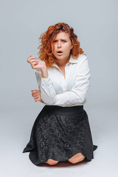 Red-haired girl dissatisfied on a gray background - Photo, Image