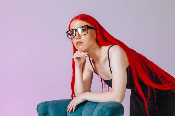 Kırmızı uzun saçlı bir kızın pembe gözlük taktığı portresi  - Fotoğraf, Görsel