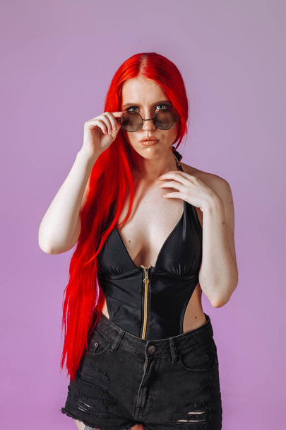 Portrait of a girl with red long hair in round glasses on a pink - Foto, Imagem