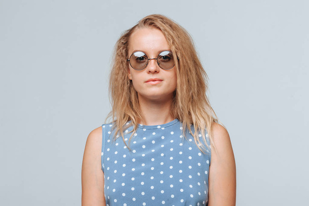 Portrait of a girl in round glasses and a blue dress on a light  - Fotoğraf, Görsel