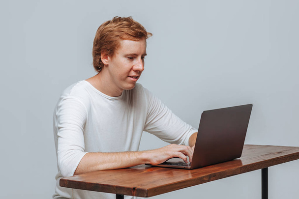 Człowiek programista siedzi na laptopie na szarym tle światła - Zdjęcie, obraz