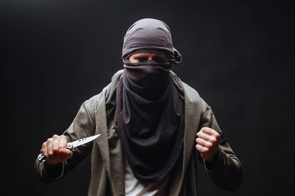 man met mes en masker op donkere achtergrond - Foto, afbeelding