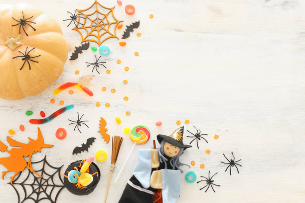 holidays image of Halloween. Pumpkins, bats, treats and cute witch over white wooden background. top view, flat lay - Foto, imagen