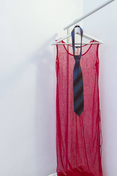 Ένα κόκκινο φόρεμα και μια γραβάτα σε μια κρεμάστρα - Φωτογραφία, εικόνα