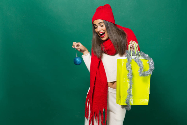 la chica sonríe y sostiene en sus manos paquetes con compras y un juguete en el árbol de Navidad. Concepto de regalo de Navidad
 - Foto, imagen