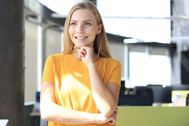 Attractive business woman looking at camera and smiling while standing in the office - Foto, immagini