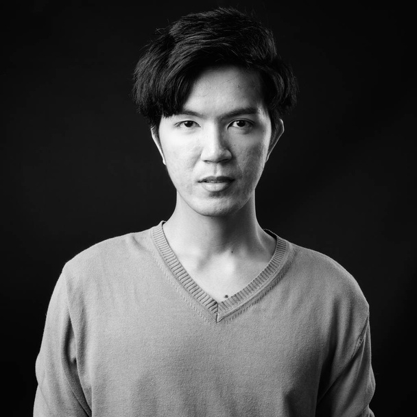 Fiatal csinos ázsiai férfi fekete háttér ellenében - Fotó, kép