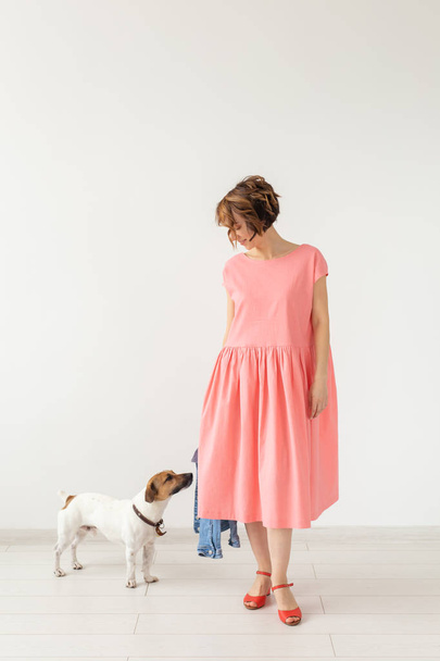 ペットと人々の概念 - 白い背景の上にジャックラッセルとピンクのドレスを着た若い女性 - 写真・画像