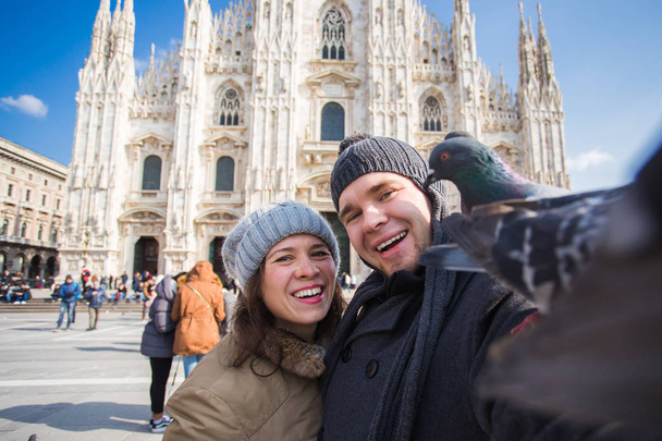 Pareja tomando autorretrato con paloma en la plaza Duomo de Milán. Viajes de invierno, Italia y concepto de relación
 - Foto, Imagen