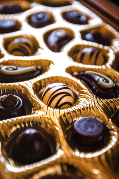 Caramelle di cioccolato di diverse forme in una scatola d'oro, una vista prospettica e sfocatura
 - Foto, immagini