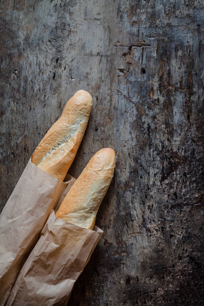 Fresh rosy baguettes on a dark wooden retro background. Top view, copy space - Photo, Image