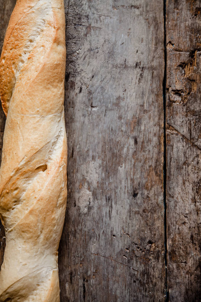 Fresh rosy baguettes on a dark wooden retro background. Top view, copy space - Photo, Image